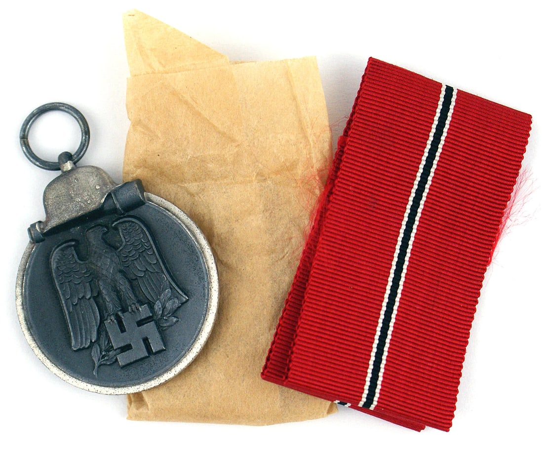 German WWII Eastern Front Medal: B-070 German WWII Eastern Front Medal. Helmet/stick grenade at top of the silver border black round medal. Relief detailed eagle/swastika/oak leaves. Reverse "WINTERSCHLACHT IM OSTEN - 1941/42" with a