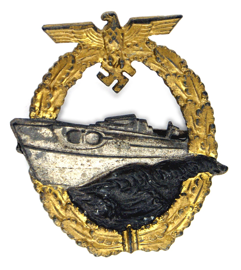German WWII Navy 2nd type E-boat Badge: B-077 German WWII Navy 2nd type E-boat Badge. Silvered E-boat/darkened waves within a dull gold oval oak leaf wreath - eagle/cut-out swastika at top, blued finish on reverse. Marked "FEC, W.E. PEEKHAU