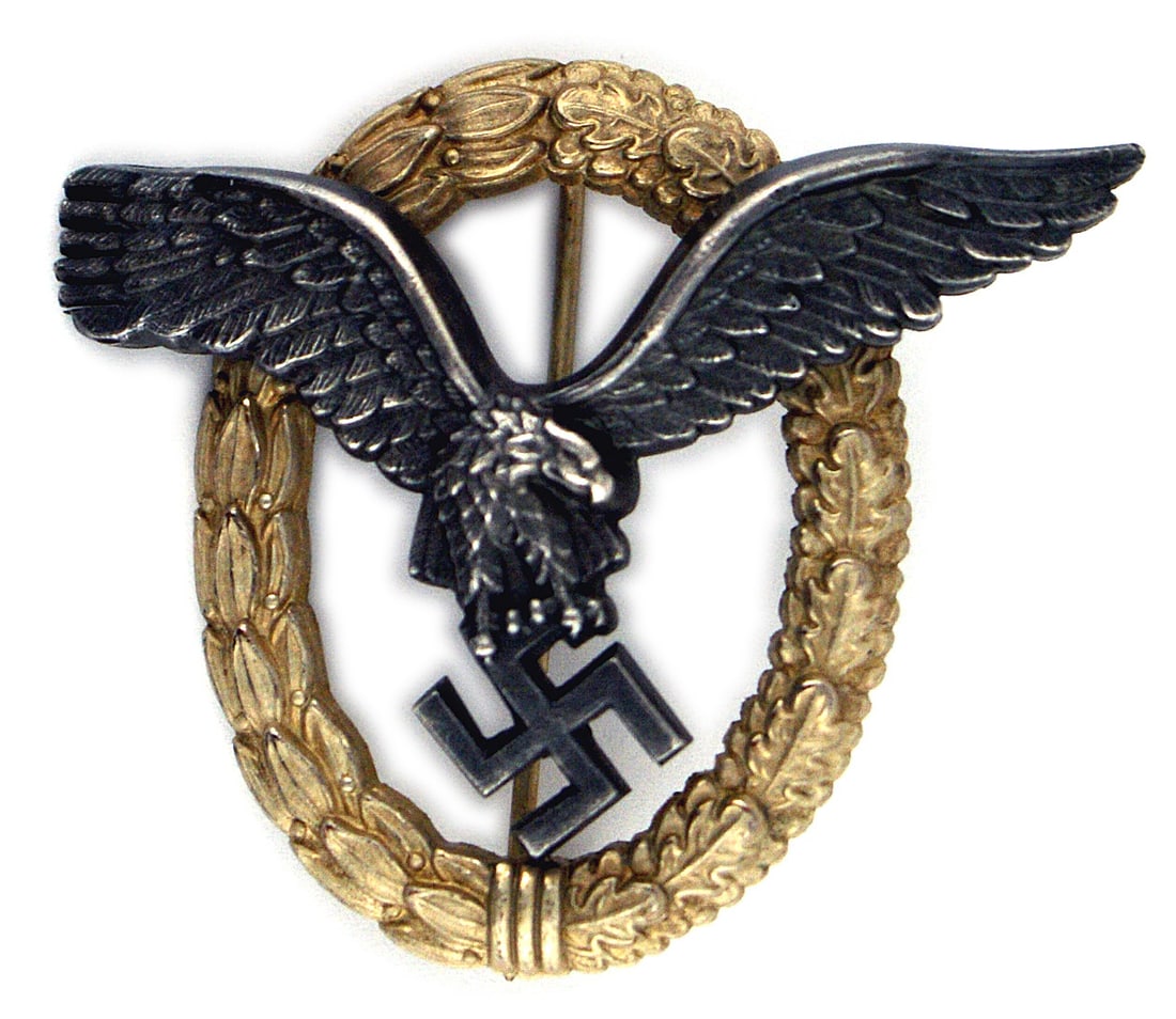 German WWII Luftwaffe Pilot Badge: B-094 German WWII Luftwaffe Pilot's Badge. Patina toned flying eagle holding a cut-out swastika. Attached to a silver detailed open palm and oak leaf wreath. Reverse is maker marked "C.E. JUNCKER - BE
