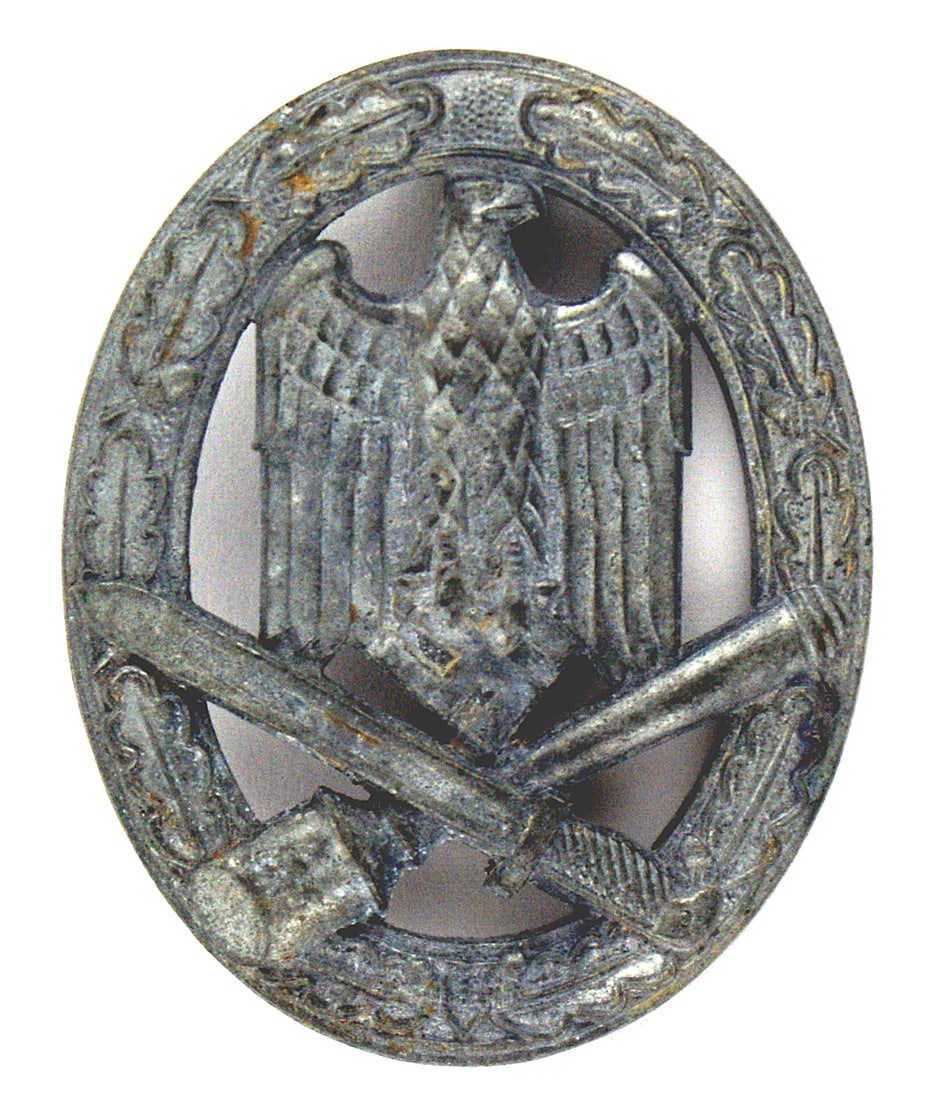 German WWII General Assault Badge: B-102 General Assault Badge. Oval open oak/laurel leaves wreath holding a tall eagle/swastika on a crossed bayonet/" potato masher" grenade. Solid type, silver finish has darkened to a gray vertical p