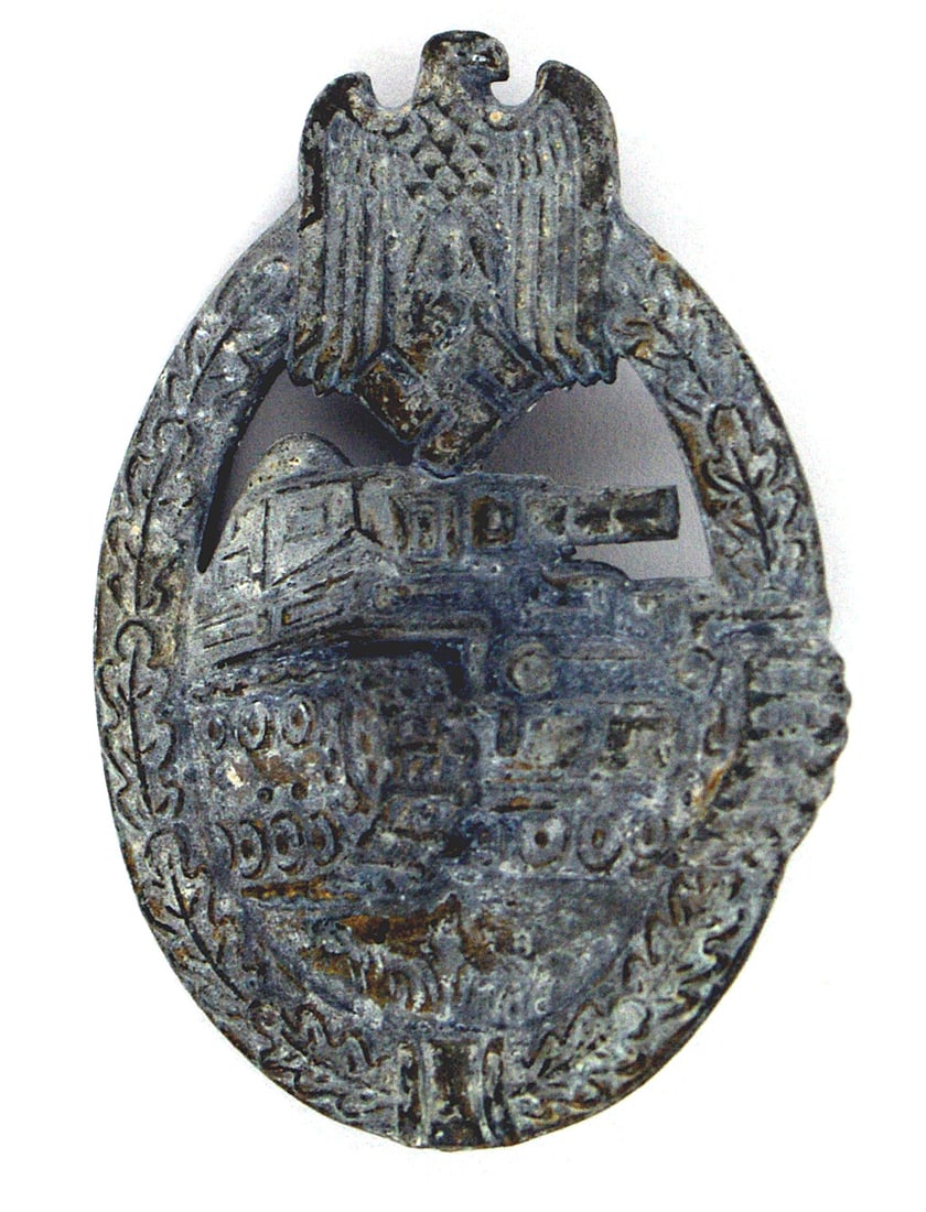 German WWII Panzer Assault Badge: B-105 German WWII Panzer Assault Badge. Attacking tank within an open oak leaf wreath - eagle/swastika at the top. Partial dished reverse. Several areas and reverse have some of the original bronze fi