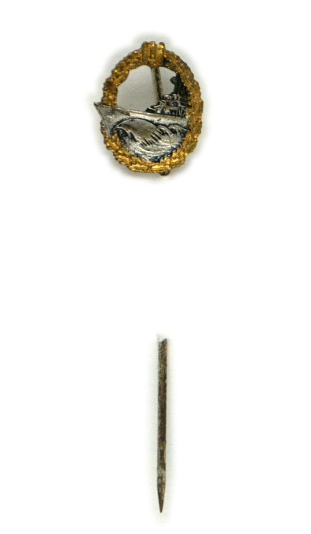German WWII Navy Destroyer lapel spiral stickpin: B-110 German WWII Navy Destroyer lapel spiral stickpin. Open gold oak leaf wreath/eagle/swastika and silver destroyer cutting through waves. Flat silvered reverse. II