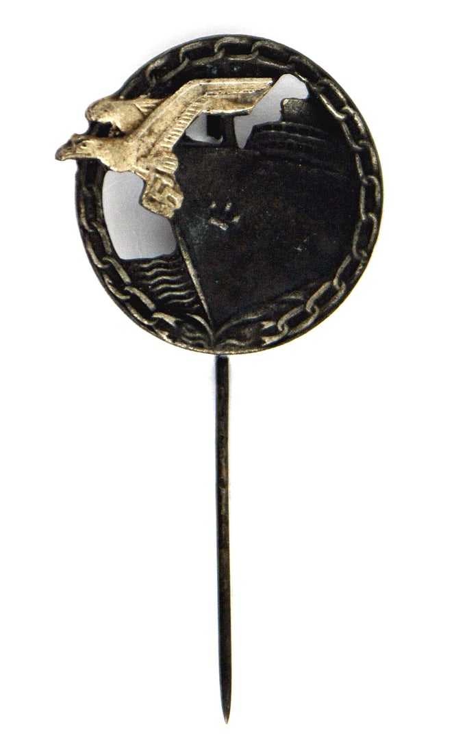 German WWII Navy Blockade Runner Badge stickpin: B-111 Navy Blockade Runner Badge lapel stickpin. Darkened round wreath holding a ship's bow with a silver eagle/swastika and link chain border. Flat back with a spiral stickpin. About the size of a US