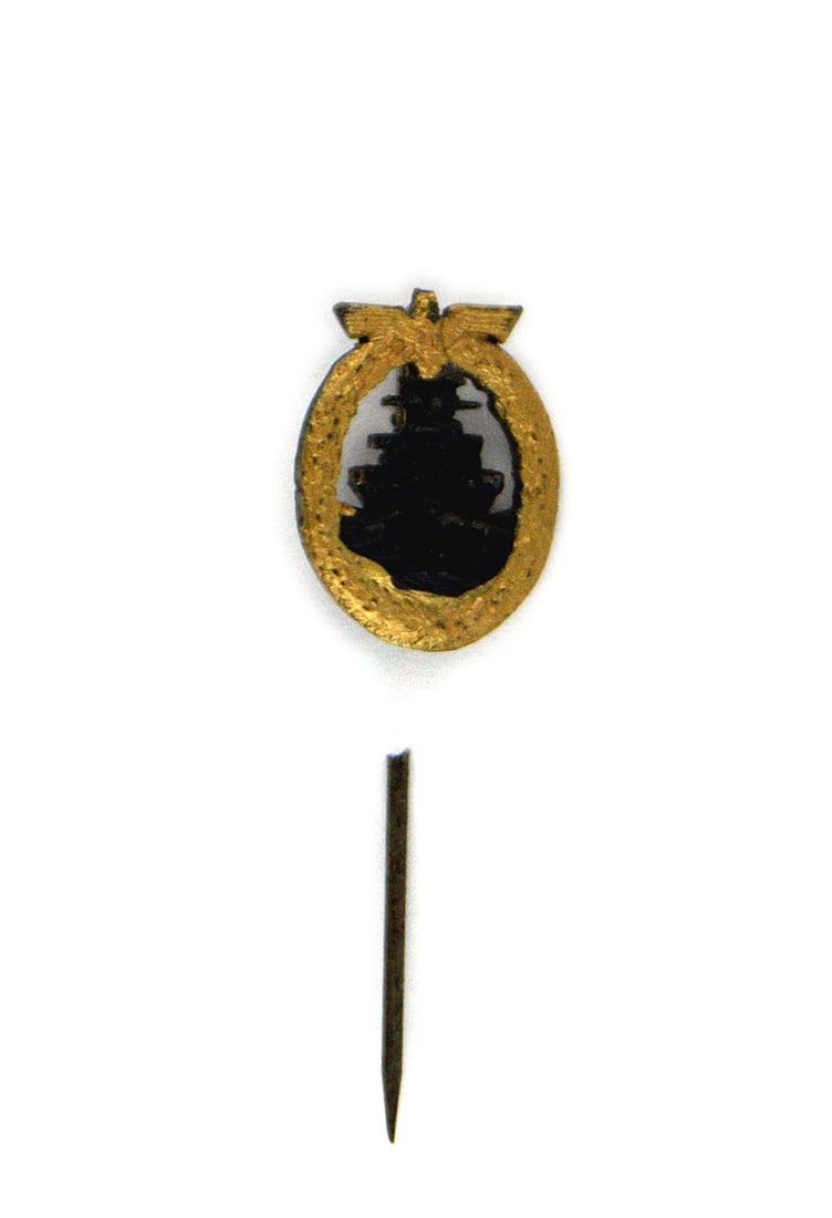German WWII Navy Fleet Service Badge lapel stickpin: B-112 German WWII Navy Fleet Service Badge lapel stickpin. Darkened high relief battleship within an open, age toned gilt oak wreath with an eagle/swastika at top. Convex shaped badge has a darkened r