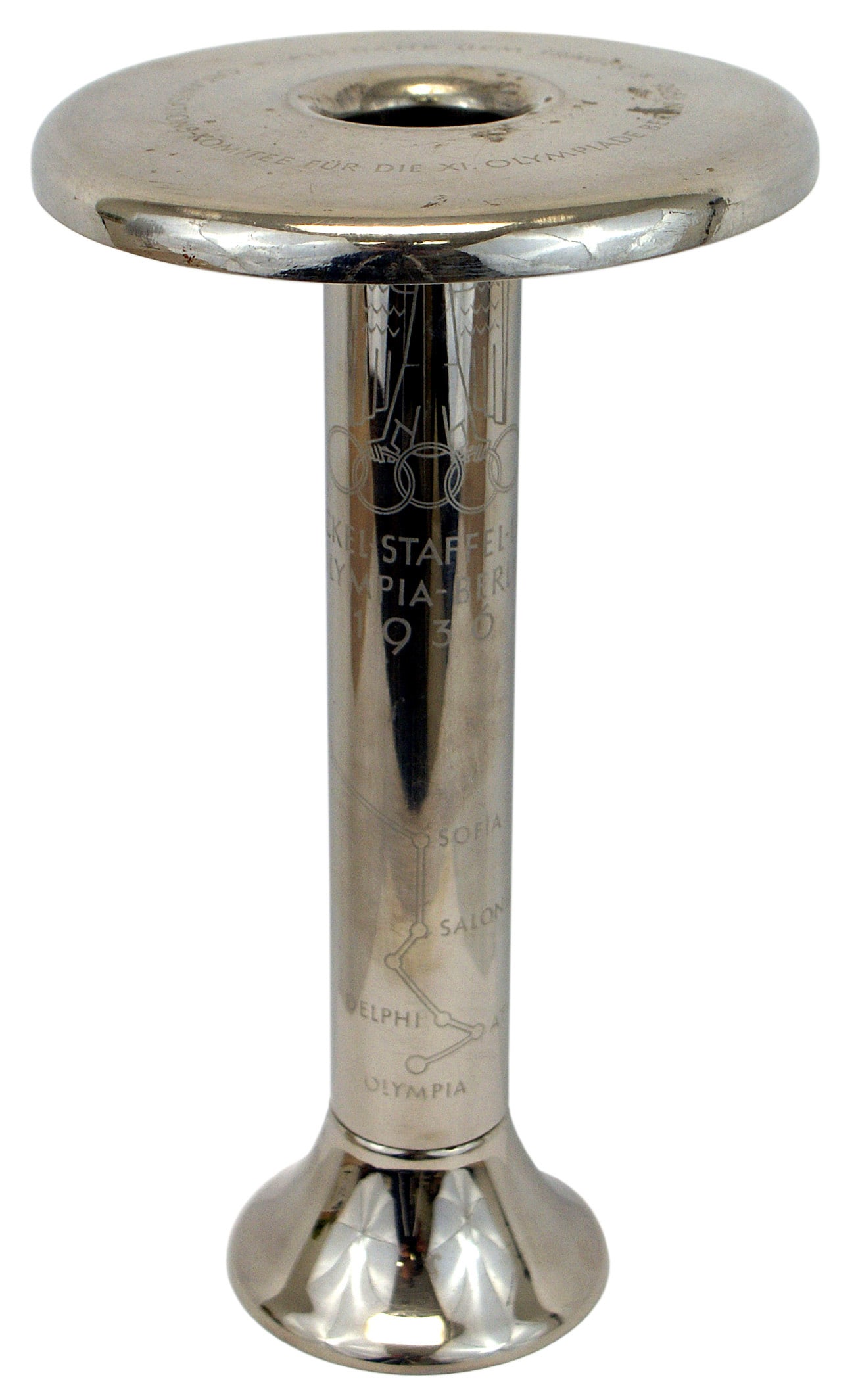 1936 Berlin Olympics Torch: A-011 1936 Berlin Olympics "Torch". 11 1/4" tall, chromed cylinder with a flared-out base and 6" diameter flat top. Staff is engraved with a map of the cities between "OLYMPIA" and "BERLIN" and the Ol