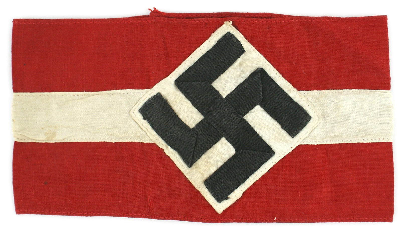 German WWII Hitler Youth Corps armband: H-014 German Third Reich Hitler Youth Corps armband. Black ribbon swastika sewn on a white square which is sewn as a triangle on a red band with a white stripe sewn down the center. Band is 3 5/8". II
