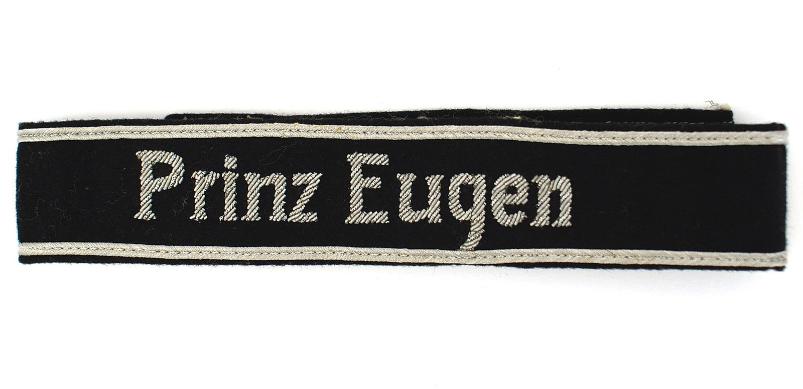 German WWII officer 7th Waffen SS cufftitle: H-022 German WWII officer's 7th Waffen SS - Freiwilligen Gebirgs-Division cufftitle "Prinz Eugen". High relief silver lettering on a soft black band with silver cord borders. II+