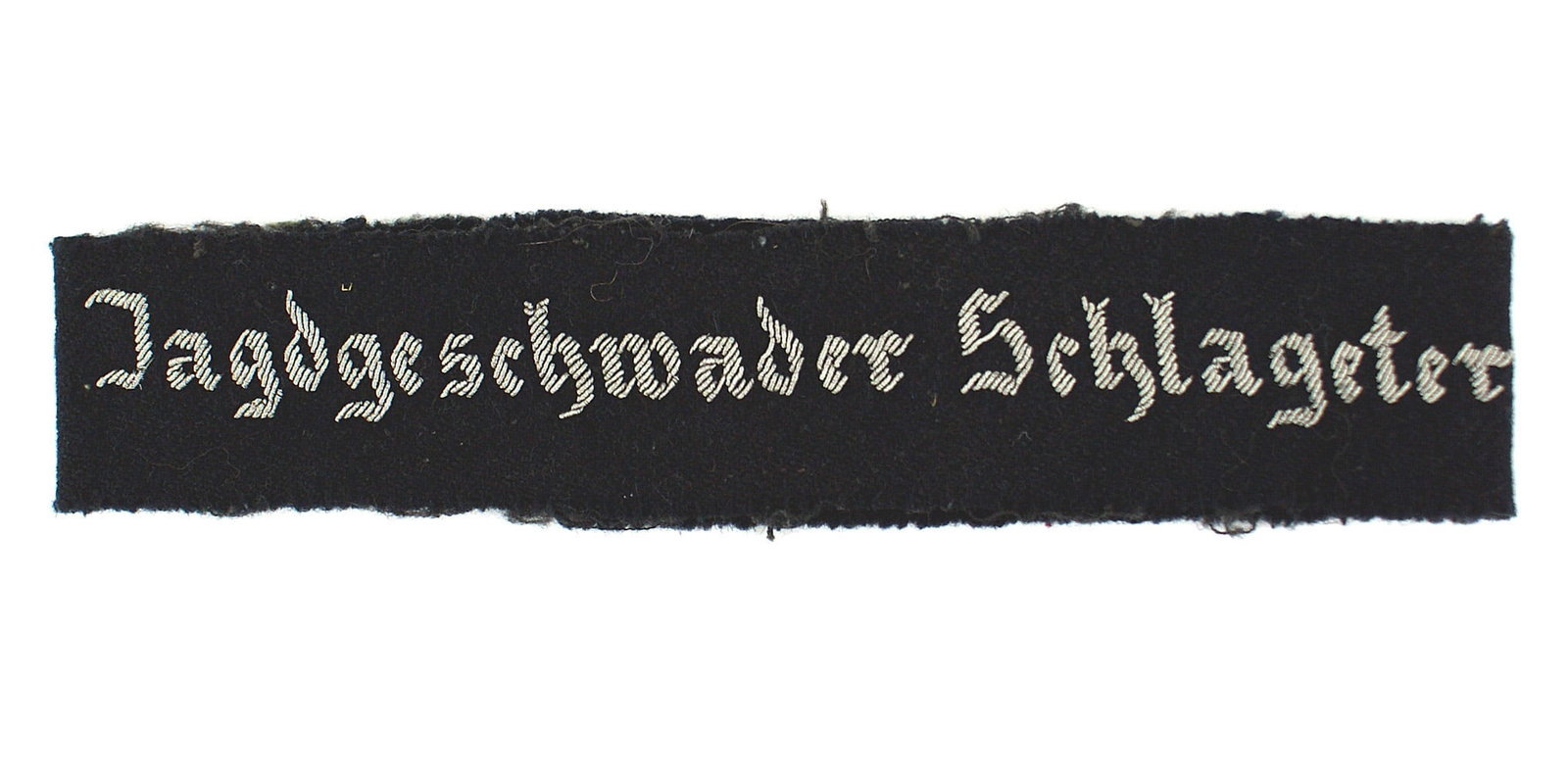 WWII Luftwaffe Schlageter cufftitle: H-023 Luftwaffe "Jagdgeschwader Schlageter" officer cufftitle. High relief embroidered age toned silver lettering on a dark blue soft cloth band. Edging shows band was removed from a tunic (Worn by me