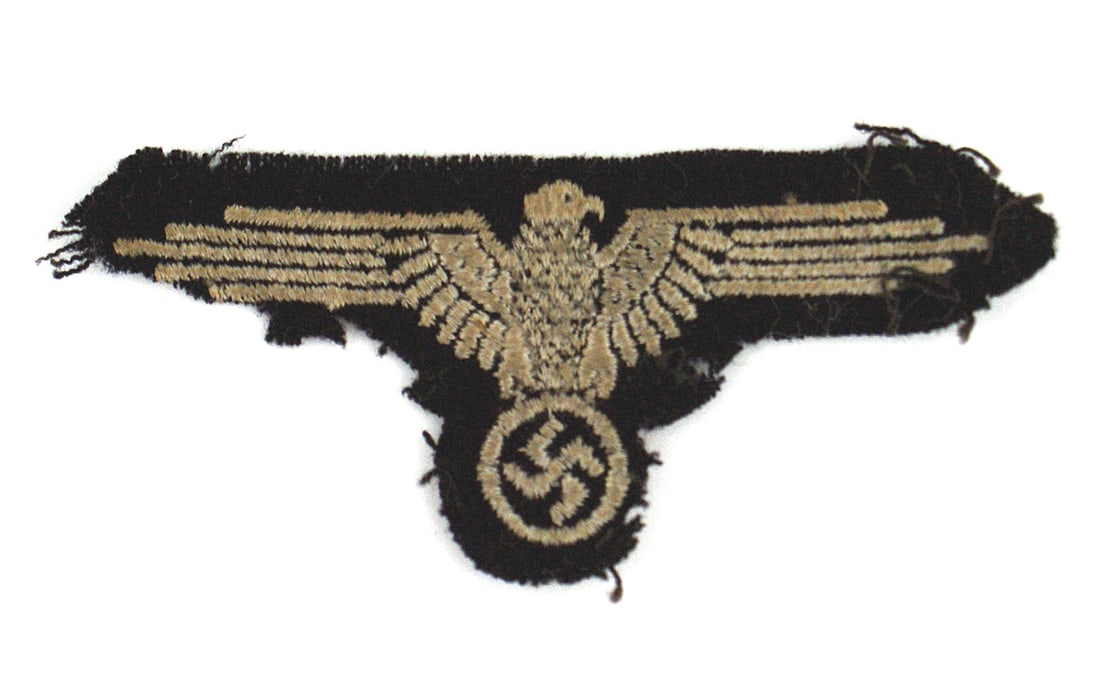 German WWII Waffen-SS SLEEVE EAGLE: H-039 German WWII Waffen-SS uniform sleeve eagle. Machine embroidered silver-gray eagle/swastika on black wool backing. Probably was taken off the arm of a captured SS man, As it shows threads and a r