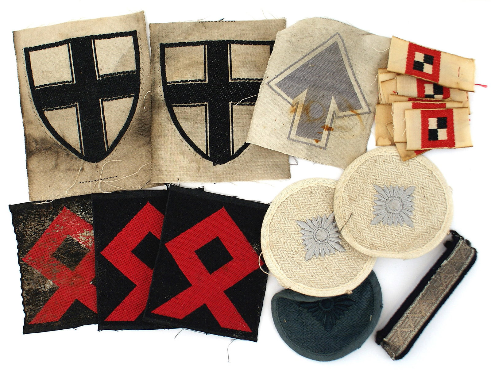 German WWII cloth lot Freikorps Runic Oval: H-046 Miscellaneous German cloth items: (1) Two East Prussia Freikorps printed shields. Uncut. Soiled. (2) Ten small, embroidered WWI Observers insignia. (3) Three Runic Oval crosses. Red bevo embroid