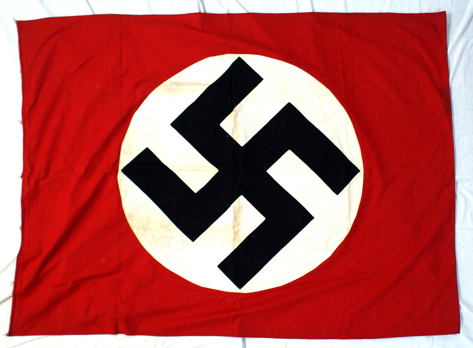 German WWII NSDAP flag huge: H-053 German Third Reich N.S.D.A.P flag. Huge black swastika sewn on a white roundel on a red field. 45" x 60". Rope tie in sleeve, border has threads where seven pole rings were attached. Both rounde