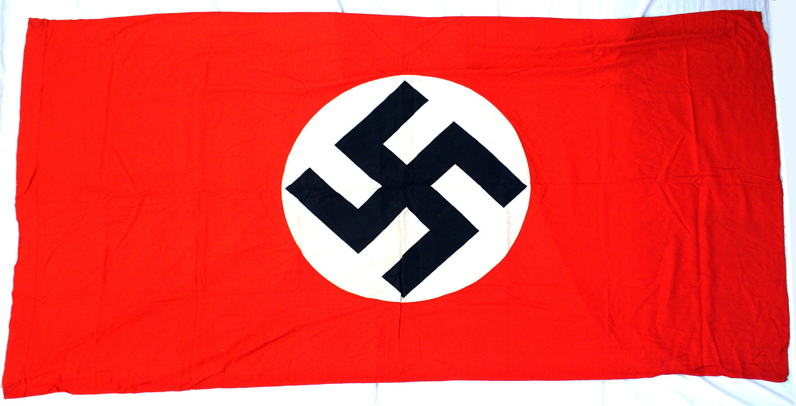 German WWII NSDAP banner: H-056 German Third Reich N.S.D.A.P banner. Large black printed swastika on a 28" diameter white circle sewn to a red field. Two - sided. Sleeve at top. 96" x 46". A little wrinkled, would still rate I
