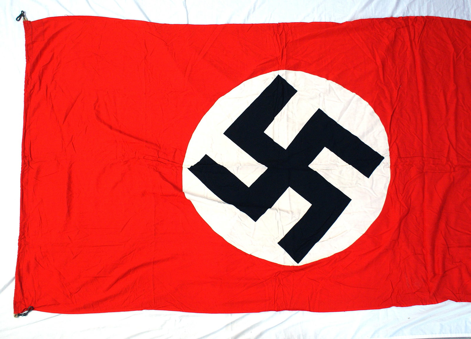 German WWII NSDAP building stadium banner: H-058 German Third Reich N.S.D.A.P building/stadium banner. Large black swastika printed on a white roundel on a red field. Reinforced corner panels. Sleeve border has a sewn - in rope with an extende