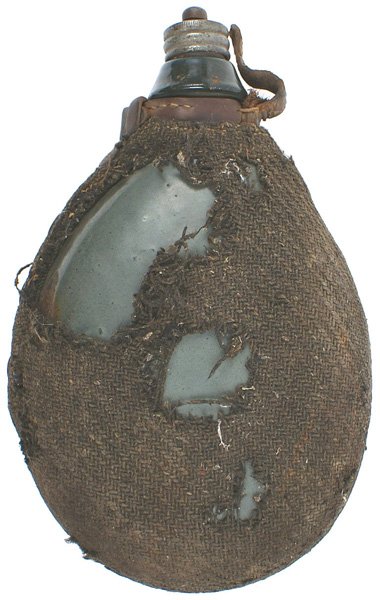 Austrian WWI officer canteen: N-66 Austrian WWI officers canteen. Gray enamel body and cork stopper, with a leather throat strap. Large area of the wicker wool cover is gone. II