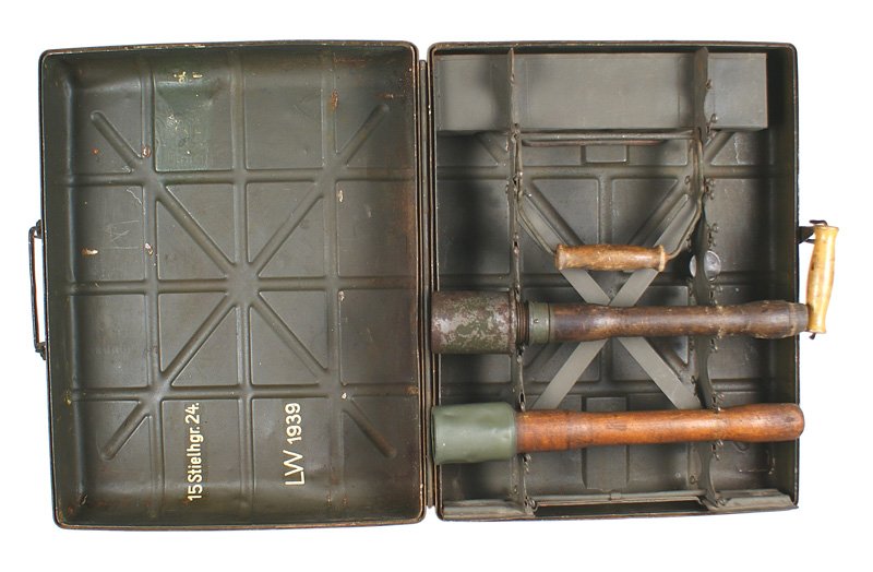German WWII grenade carrier: M-087 German WWII grenade carrier. 15" x 18 3/4" x 5 1/4". O.D. steel container with a wood carrying handle. Inside steel frame can accommodate 15 stick grenades. Underside of lid has white stenciling