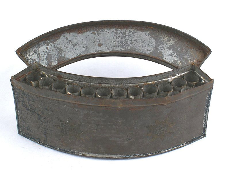 Early American Militia belly box: K-011 Early American Militia "belly box". 9" curved construction with a hinged lid and soldered-on tin belt loops. Has 25 separate paper cartridge holders. Only residue of the japanned finish remains,