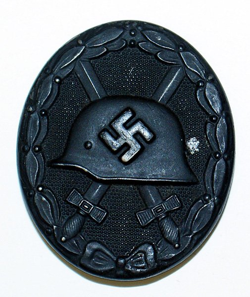 German WWII 1939 Wound Badge Black medal: B-073 German WWII 1939 Wound Badge - Black. Relief helmet with a swastika and crossed swords. Reverse marked "65" (Klein & Quenzer in Idar/Oberstein). II