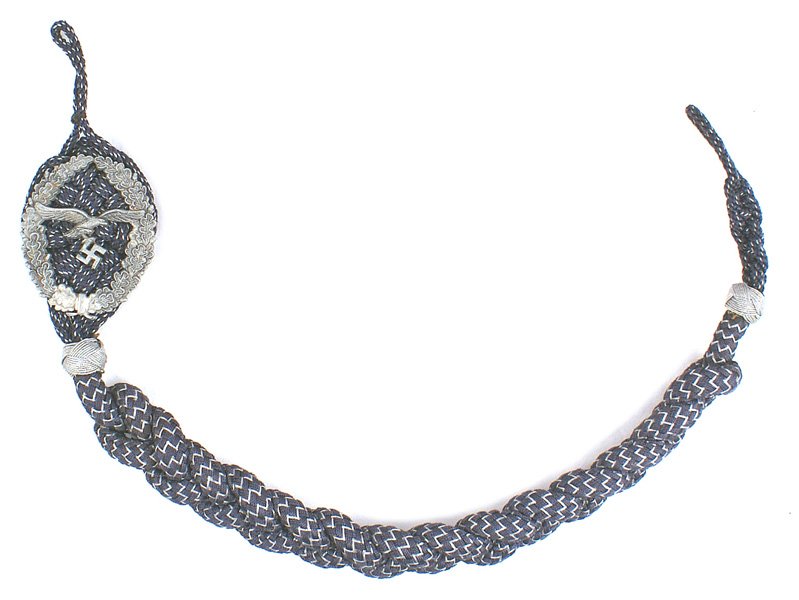 German WWII Luftwaffe Marksmanship Lanyard: B-089 German WWII Luftwaffe Marksmanship Lanyard. Flying eagle/swastika on an open oak leaf wreath affixed to a knotted blue-gray cord with silver flecking. Heavy twisted cord extension with silver wi