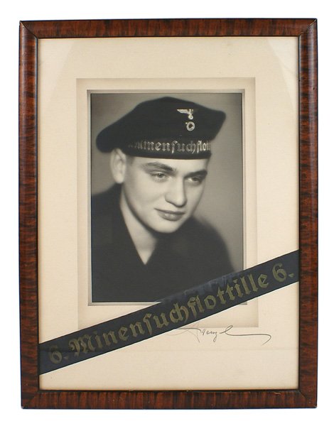 Photo of a German WWII seaman Donald Duck hat: L-008 Framed portrait photo of a German WWII seaman wearing a "Donald Duck" hat. With "6. Minensuchflottille 6." tally across bottom of photo. Mat signed by artist "A. Henzl". 16 1/8" x 12 1/4". II