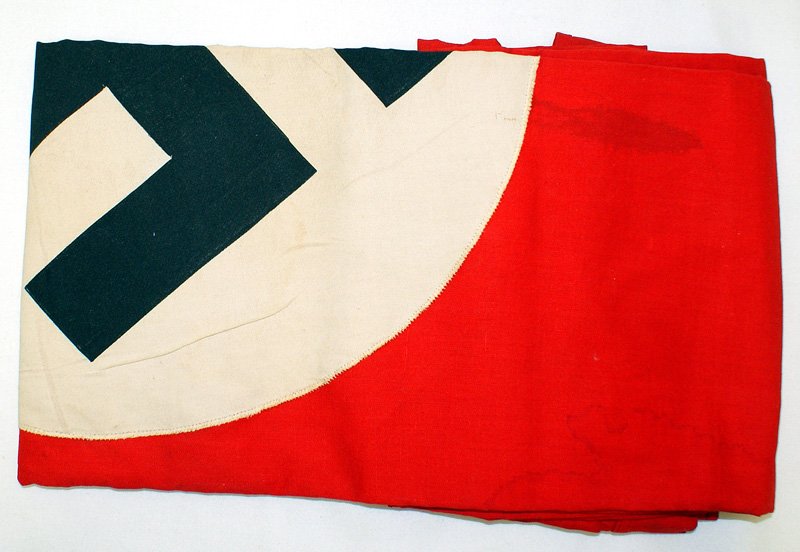 German WWII NSDAP banner flag: H-086 German WWII N.S.D.A.P. banner. Black printed swastika on a white disc, sewn to red field. 54" x 30". Two-sided with a cord sleeve. N.S.D.A.P. ink stamping. Several small water stains. II