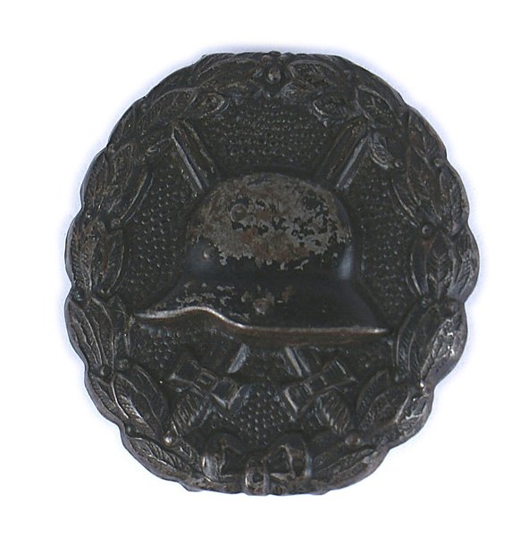 German WWI Wound Badge Black: B-017 German WWI Wound Badge - Black. Relief helmet with crossed swords on a pebbled background within an oak leaf wreath. II