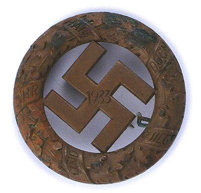 German WWII Gau Munich Badge: B-042 German WWII Gau Munich Commemorative Badge of 9 November 1923. Bronze circular oak leaf wreath holding a cut-out swastika with "1933". Reverse is maker marked "DESCHLER & SOHN MUNCHEN 9". Pin-ba