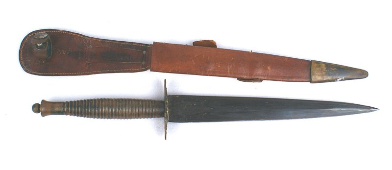 British WWII Fairbairn-Sykes fighting knife: D-198 Fairbairn-Sykes with a one-piece ribbed brass grip/ball pommel nut. Thin brass oval guard. Possibly period replaced 7 3/8" double-edge slightly elliptical blued blade. Lighter brown leather scab