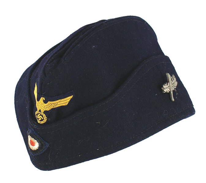 German WWII Navy EM Submariner o'seas cap: E-092 German WWII Navy EM Submariner's "bordmutze" (o'seas cap). Bevo type gold eagle/swastika and rosette on a dark blue cap. Silvered U-143 insignia (crossed pine branch/machete) pinned to side. Bla