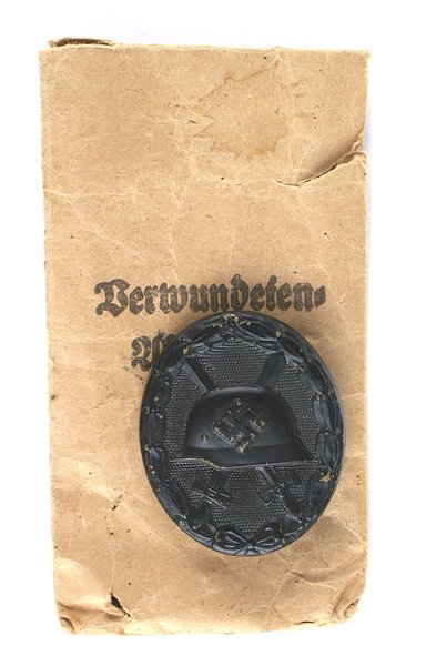 German WWII Wound Badge Black: B-076 German WWII Wound Badge - Black. Relief swastika/helmet and crossed swords on a pebbled background. With an oak leaf border. Reverse is marked "30" (Hauptmunzamt in Vienna). With an issued named