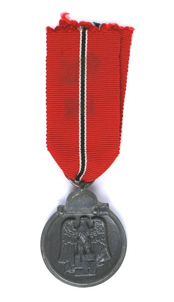German WWII Eastern Front Medal: B-087 German WWII Eastern Front Medal. Darkened finish on a silvered perimeter with a helmet/stick grenade. Obverse bears a relief black/gray eagle/swastika. Reverse "WINTER BATTLE IN THE EAST 1941/42