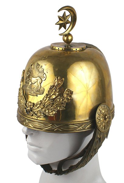 Persian Qajar dress helmet Circa 1880-1890: R-002 Persian Qajar period dress helmet. Probably a palace guard. Gilt brass skull with a relief "ribbon bow" pattern border. Rounded top base holding a round ball finial/crescent and star decoration.