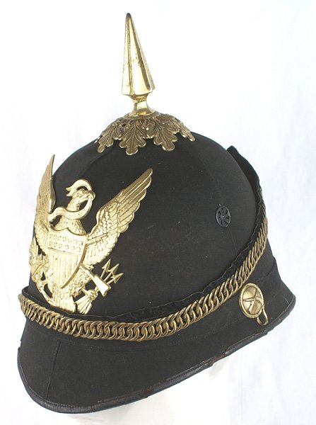 U.S. M1884 cork helmet: K-063 U.S. M1884 cork helmet. Soft blue cloth covered body. Large gilt American eagle/shield/crossed rifles front plate, spike (small dent)/oak leaf base, side bosses and chain type chinstrap. Leather