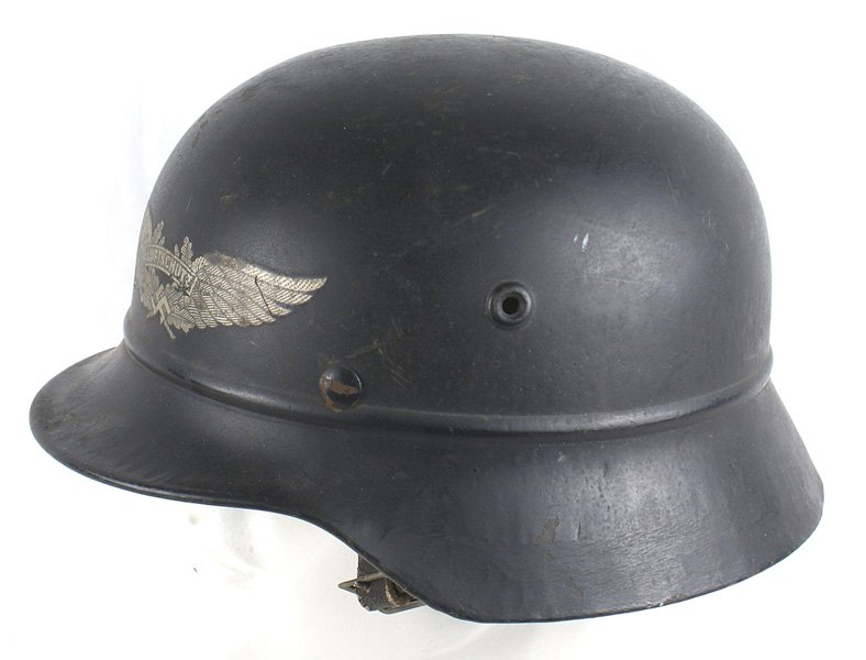 German WWII Luftschutz M1940 helmet: E-048 German WWII Luftschutz M1940 helmet with a bead around the base of the skull. Large Luftschutz/winged swastika decal. 90% original dark blue finish. Leather chinstrap and liner which show much u
