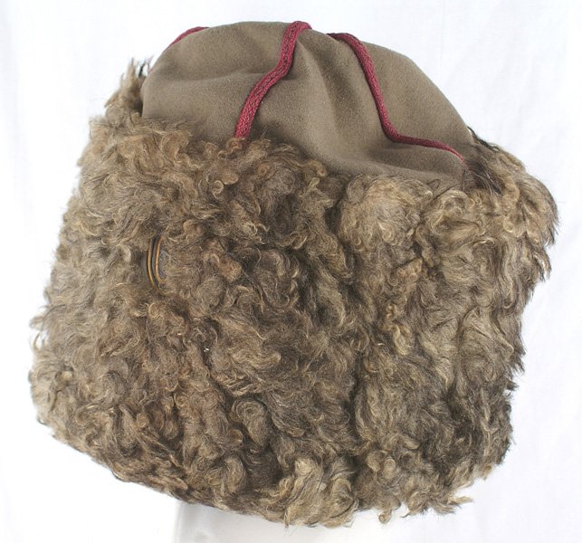 Russian WWI papacha hat: E-142 Russian WWI "papacha". A light OD cloth body with a heavy red cord piping around the crown and forming a cross on the center of the top. Imperial Russian oval metal rosette with blue and yellow 