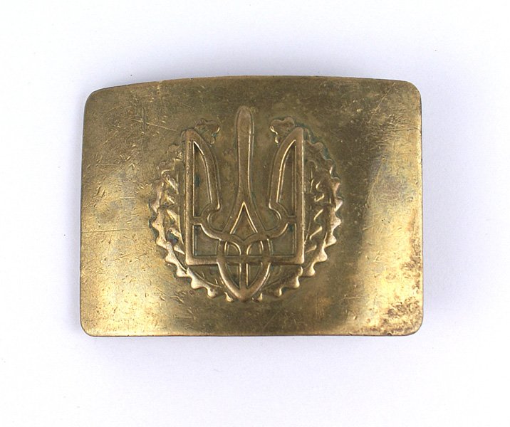 Ukranian WWII brass belt buckle: H-035 Ukranian WWII brass belt buckle. Convex shape with a relief embossed trident emblem on an oak leaf wreath. Reverse has a brass "tongue", belt brace and roller bar. 2 7/8" x 2 1/8". II