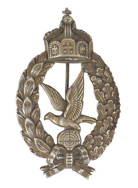 Prussian WWI Aerial Gunner Badge: B-021 Prussian WWI Aerial Gunner Badge. Field issued silvered stamped variety. Pronounced large Hohenzollern Crown on the top of an open oak/laurel leaf wreath. Center holds an eagle with turned-up wi