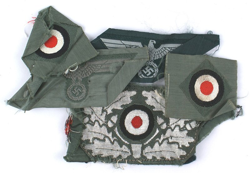 Lot of Third-Reich cloth cap insignia: E-128 Lot of Third-Reich cloth cap insignia: (1) Bevo gray on green o'seas cap eagle. Uncut. (2) Similar but darker gray on lighter green. Uncut. (3) Bevo - embroidered flat silver oak leaves with a r