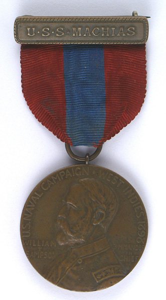 U.S. Sampson Medal: B-283 Sampson Medal. Bronze pin-back ship's bar "U.S.S. MACHIAS". Profile of Admiral Sampson on the obverse. Reverse has relief view of three Navy men "at the ready" and "CARDENAS-MAY 11". Rim is impr