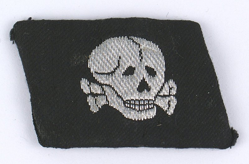 German SS Panzer Division collar tab: H-039 German WWII SS Panzer Division "Totenkopf" Officers collar tab. Silver embroidered skull appears to have an almost waffle pattern. Identical to the one picture on the upper right hand corner on 