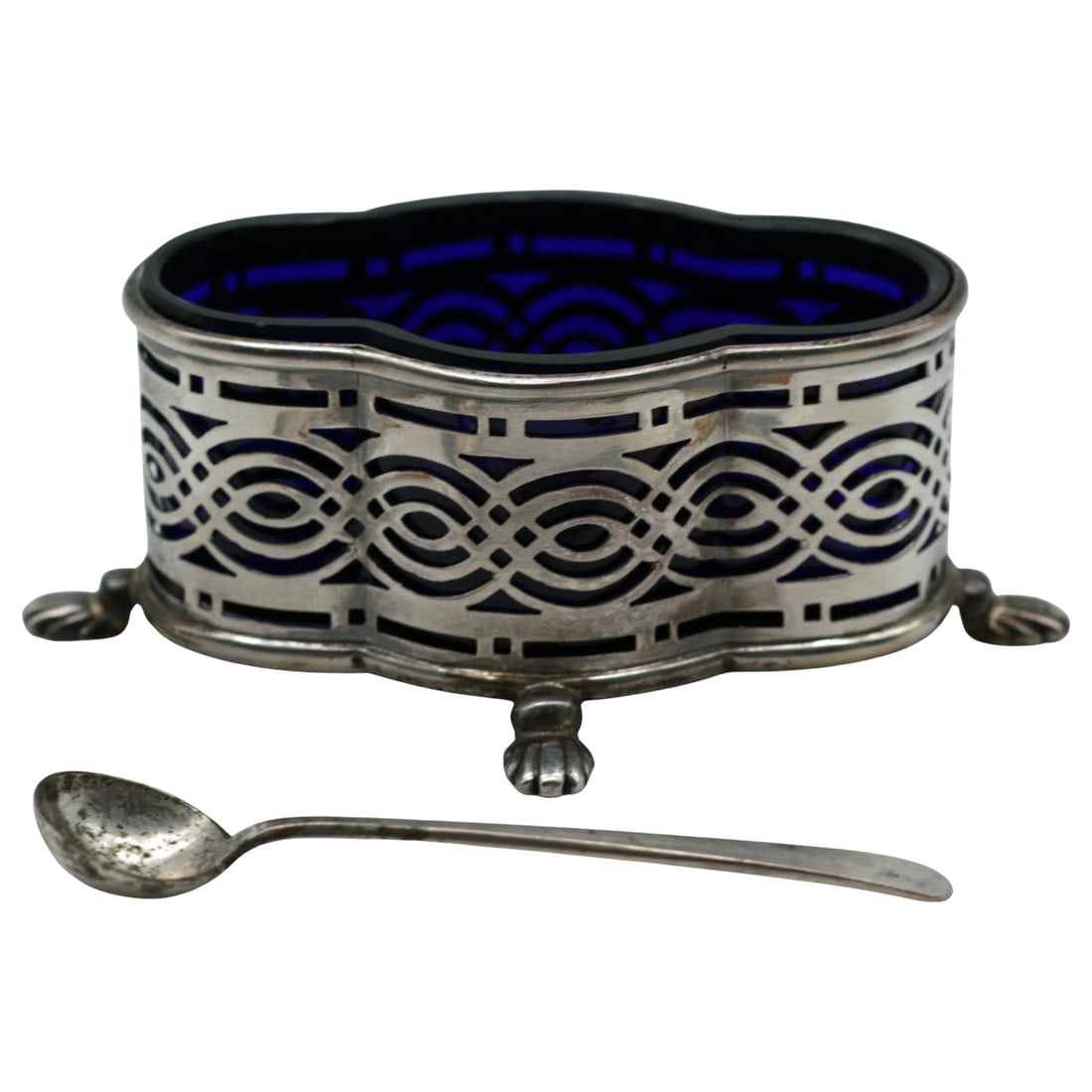 Edwardian Sterling Silver Cobalt Glass Open Condiment with Spoon: Summary Hallmarked Birmingham sterling silver open condiment or master salt with pierced Art Deco influenced geometric surround, raised on four stylized paw feet and fitted with a shaped cobalt blue g