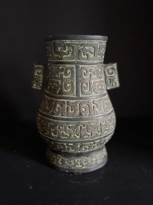An archaic-style vase with taotie motifs: Archaic-style vase cast in relief with stylised taotie masks and geometric scroll patterns, the body of baluster form with applied lug handles at the shoulders,