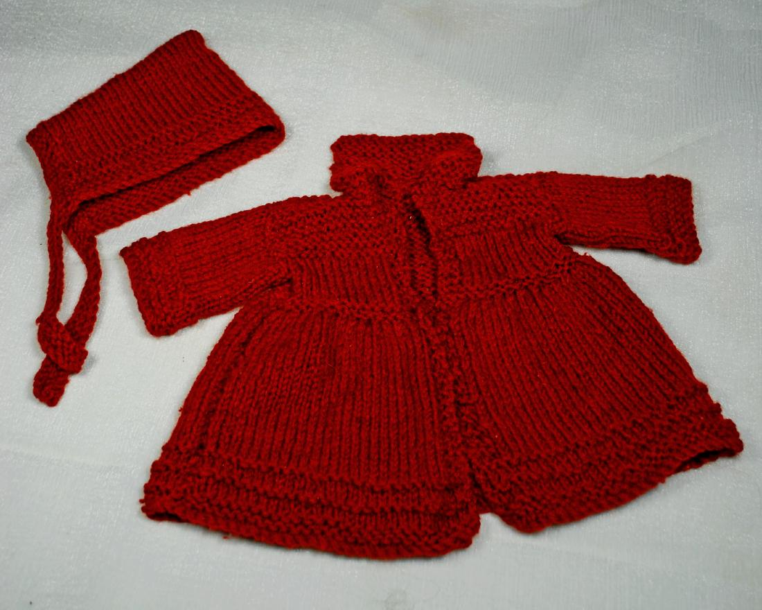 104. MAROON WOOLEN COAT AND BONNET. Wool knit coat has: 104. MAROON WOOLEN COAT AND BONNET. Wool knit coat has square collar, open front, slightly gathered skirt, decorative detail on bodice, sleeves and hemline, 5 ½” shoulder width, 8 ½