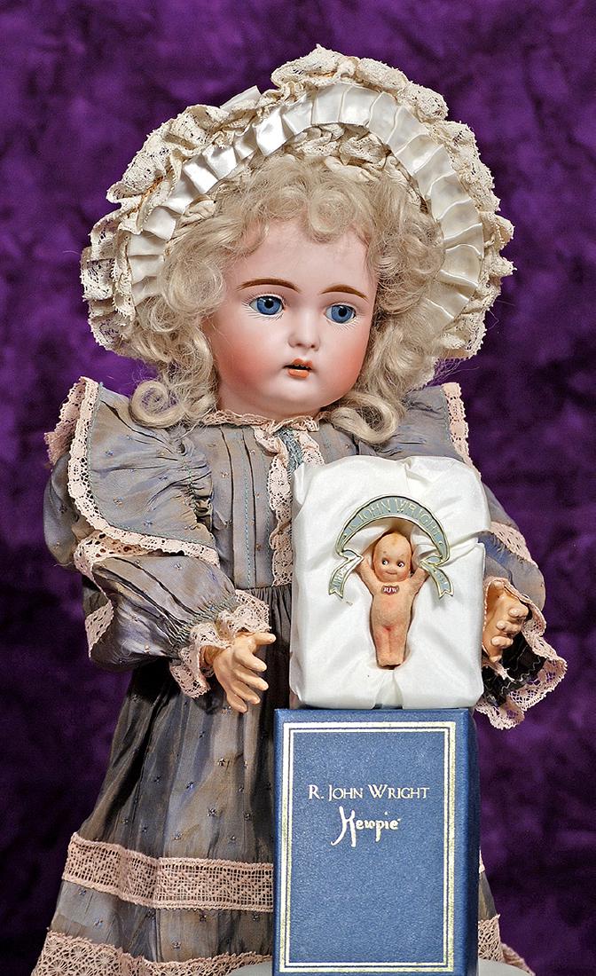 129. R. JOHN WRIGHT UFDC KEWPIE BOUTONIERRE. 2 ½: 129. R. JOHN WRIGHT UFDC KEWPIE BOUTONIERRE. 2 ½” felt Kewpie with painted features, holding foil banner embossed “R. John Wright UFDC 1999”. Brass clasp on reverse. Commentary: