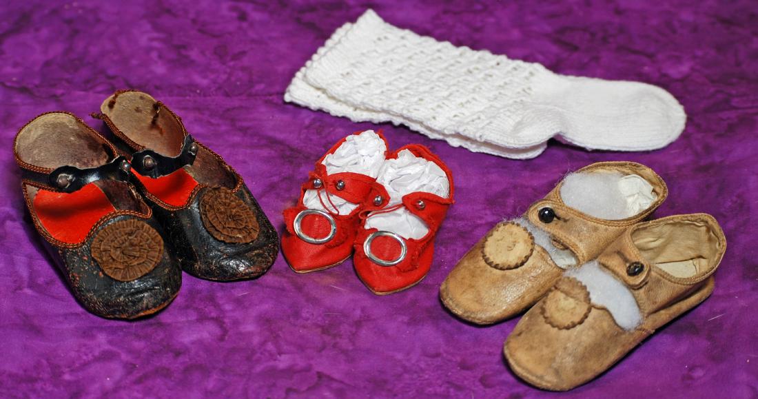 240. THREE PAIR OF ANTIQUE DOLL SHOES. 4” L. pair: 240. THREE PAIR OF ANTIQUE DOLL SHOES. 4” L. pair of French dark leather shoes with ankle strap closing and silk rosettes, original French markings on soles; 3” pair of red cloth shoes wit