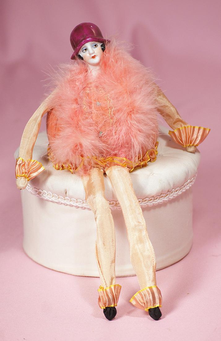 192. GERMAN PORCELAIN ART DECO DOLL AS PINCUSHION.: 192. GERMAN PORCELAIN ART DECO DOLL AS PINCUSHION. Marks: Germany. Porcelain head with molded burgundy flapper hat and short black hair, painted side-glancing brown eyes with outlined and eyeshadow, c