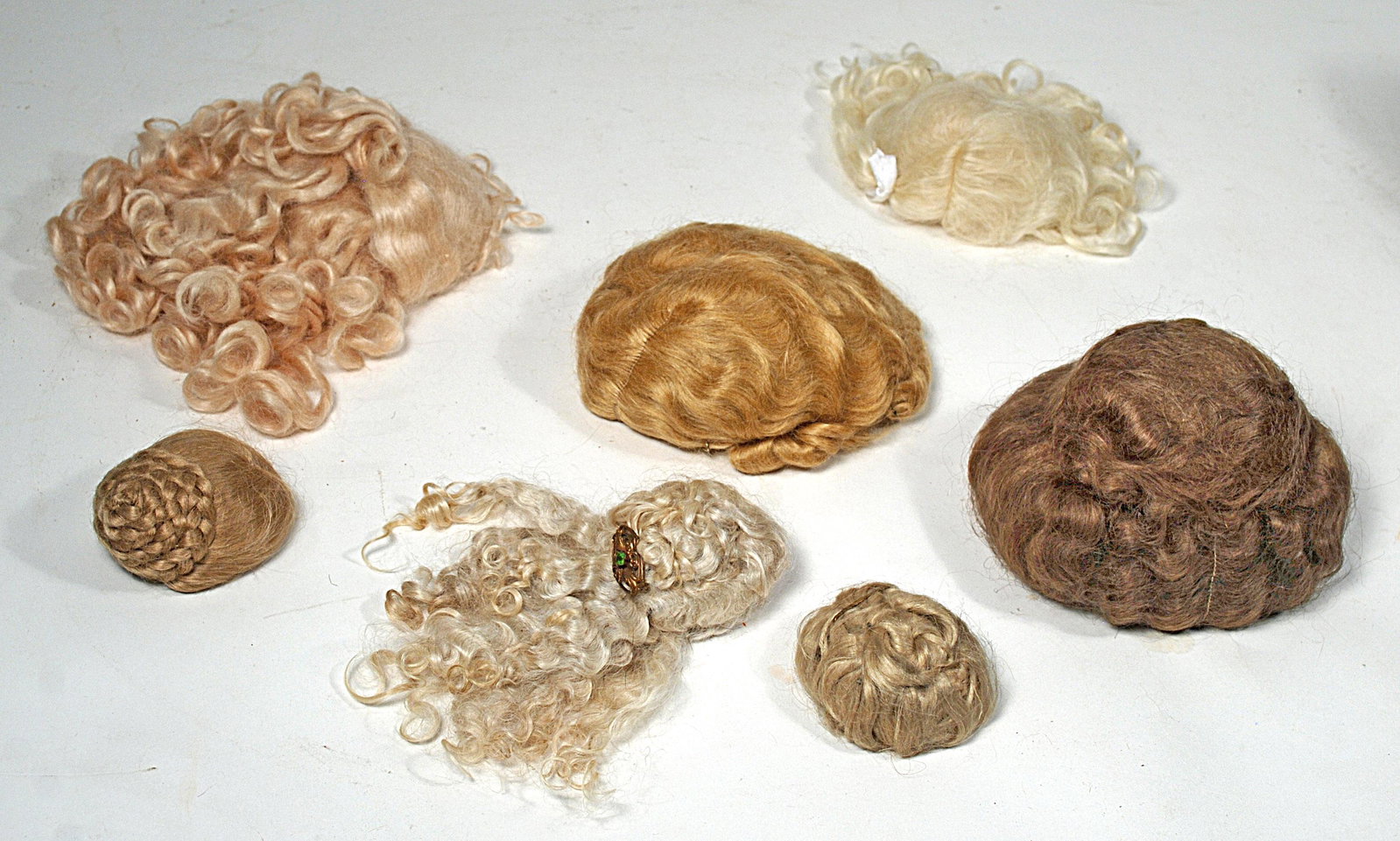 ASSORTMENT OF ANTIQUE & CONTEMPORARY DOLL WIGS: ASSORTMENT OF ANTIQUE & CONTEMPORARY DOLL WIGS Includes: Antique brown wig in Gibson Girl style, for 9"10" head circumference; antique blonde mohair upsweptstyle wig for 4" head circumference; five co
