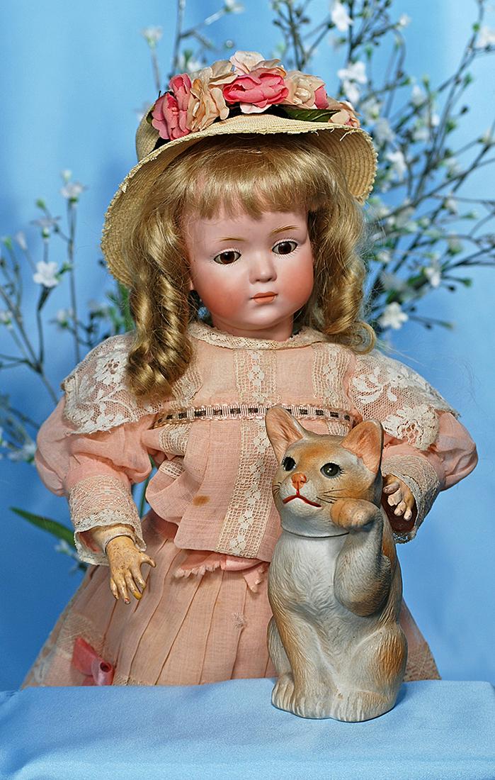 ANTIQUE GERMAN ALL-BISQUE KITTEN AS CANDY CONTAINER.: ANTIQUE GERMAN ALL-BISQUE KITTEN AS CANDY CONTAINER. Marks: 4. 5 ¼". All-bisque kitty has inset brown glass eyes, painted pink nose, red mouth and black whiskers, one jointed front paw in uplifted po