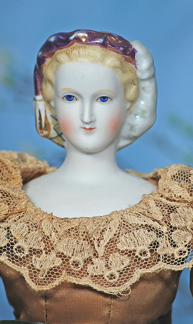 GERMAN BISQUE PARIAN LADY KNOWN AS "EMPRESS EUGENIE": GERMAN BISQUE PARIAN LADY KNOWN AS "EMPRESS EUGENIE" WITH ELABORATE LUSTRE TRIM AND SNOOD. 16 ½". Bisque shoulderhead with slender oval face, sculpted blonde hair with green painted snood decorated w