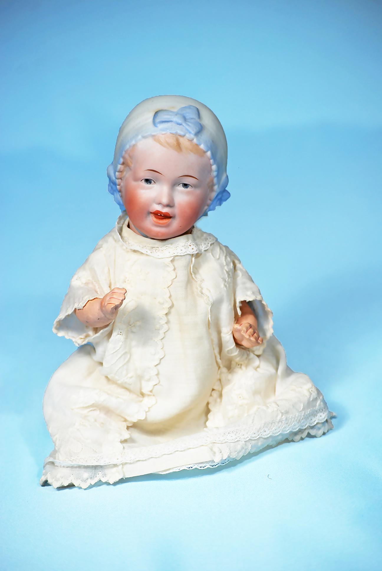 GERMAN BISQUE BABY WITH SCULPTED BLUE BONNET. Marks:: GERMAN BISQUE BABY WITH SCULPTED BLUE BONNET. Marks: 22-7. 9". Bisque socket head, light brown hair peeking from under sculpted and shaded blue bonnet with three bows, painted features, intaglio blue 