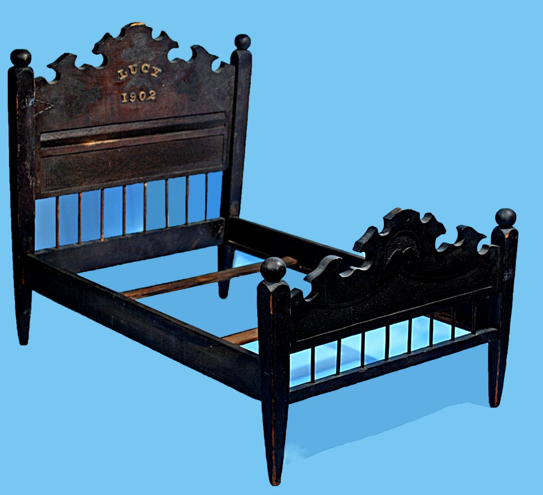 VICTORIAN WOODEN DOLL BED: 328. VICTORIAN WOODEN DOLL BED. 25” L x 19” H. x 15” W. Dark walnut finish, carved wooden doll bed marked “Lucy 1902” on the headboard. Very good condition. Estimate: $50/75